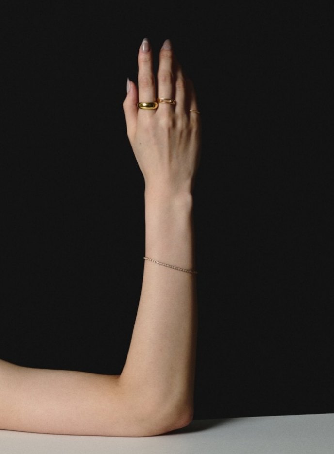 Raised arm with gold rings against black