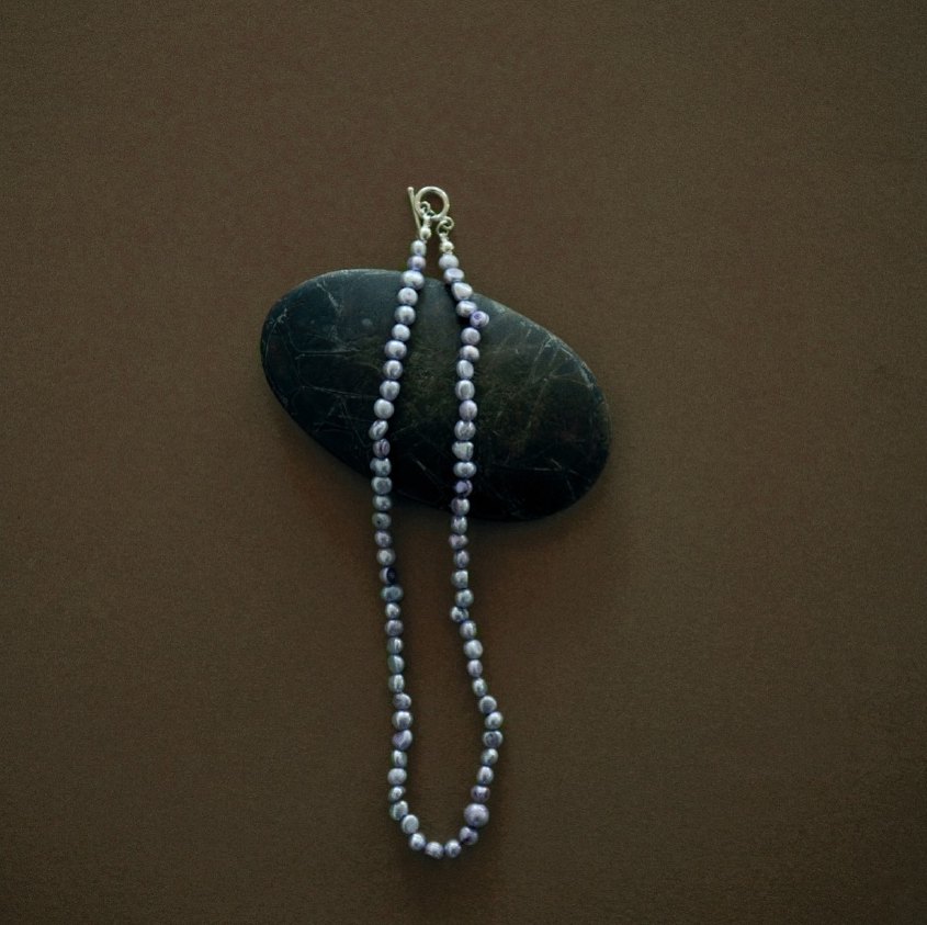 Pearl necklace draped over a dark stone