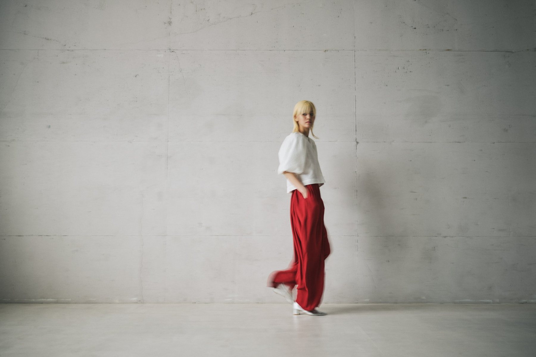 Model in a white top and red wide trousers