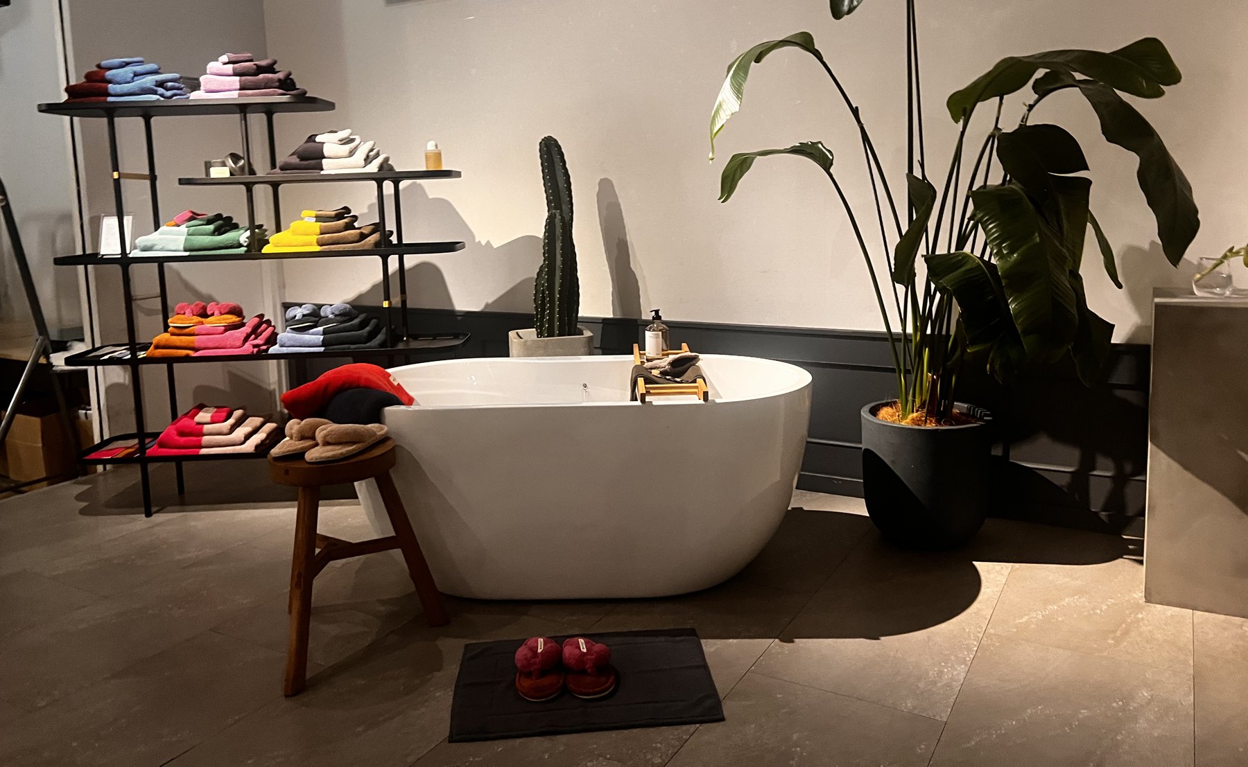 Towels, slippers and a freestanding bathtub styled in a showroom