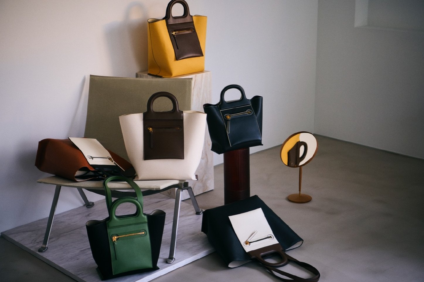 Still life of structured tote bags in yellow, green and black on a chair