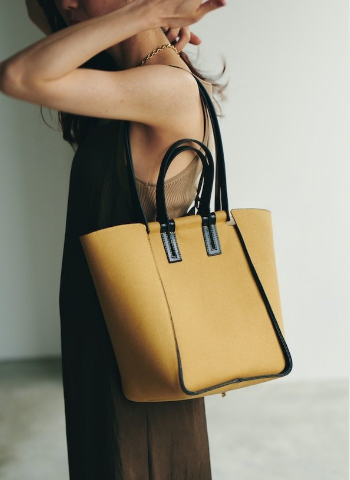 Woman carrying a mustard tote over her shoulder