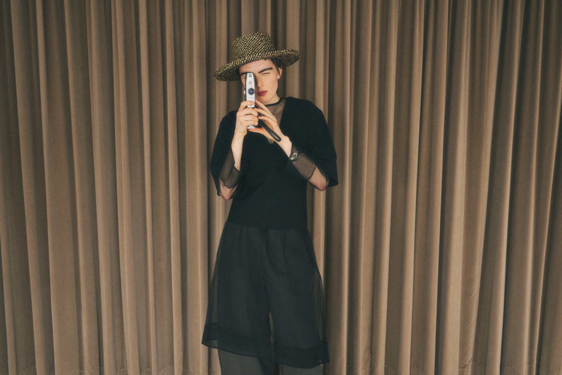 Model with a vintage film camera in front of a velvet curtain